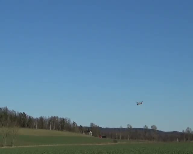 A drone above a tree-lined field in external recorded development footage
